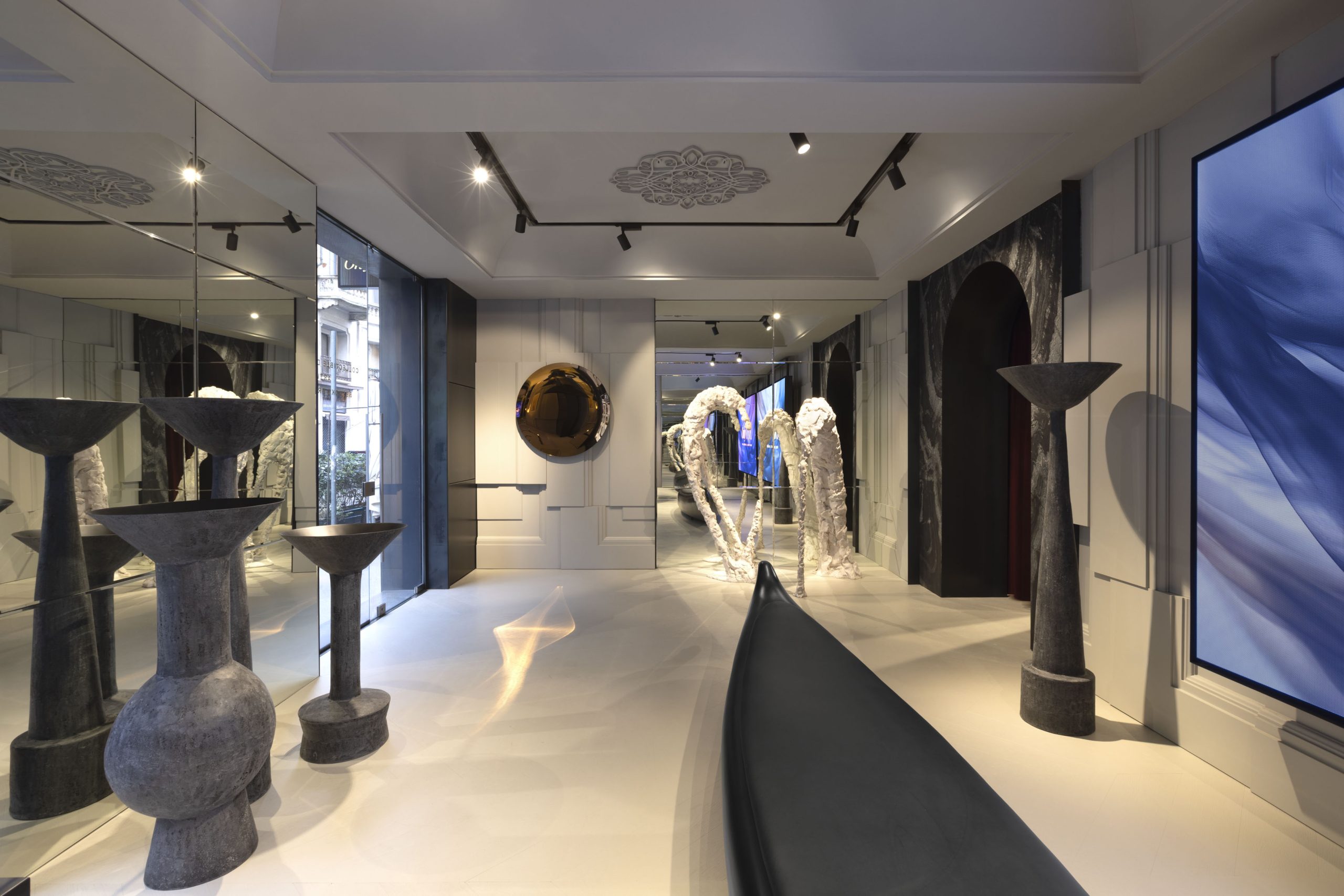 Atelier Online di OnlyONE: una collezionista consulta la boutique digitale in un interno con vista serale su Milano
